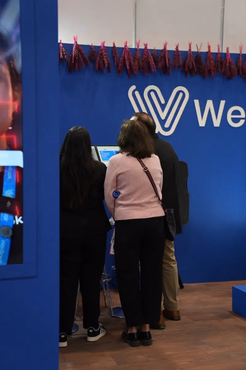 Visitantes reciben una demostración de WeiBook en un stand de México