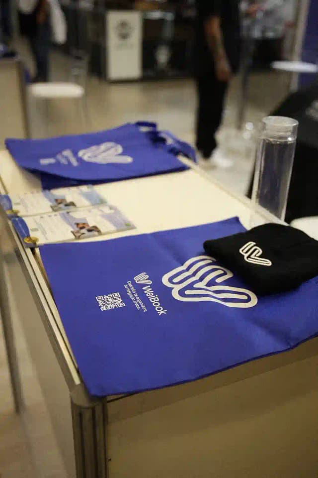 Material promocional de Weibook con folletos y gorro en stand de evento