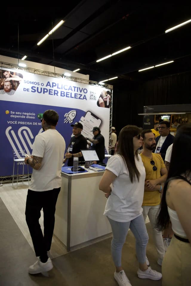 Visitantes en feria explorando el stand de Weibook, software para belleza y reservas